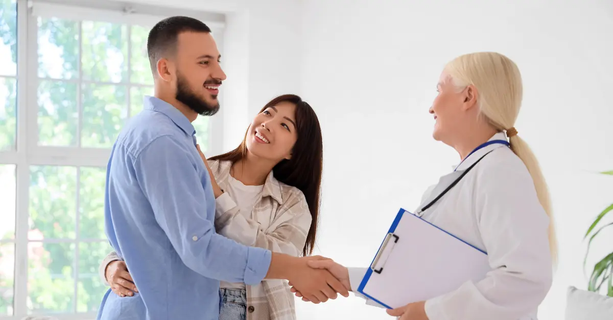 Fertility center hormone evaluation explained by a doctor pointing to reproductive charts during a couple’s consultation.