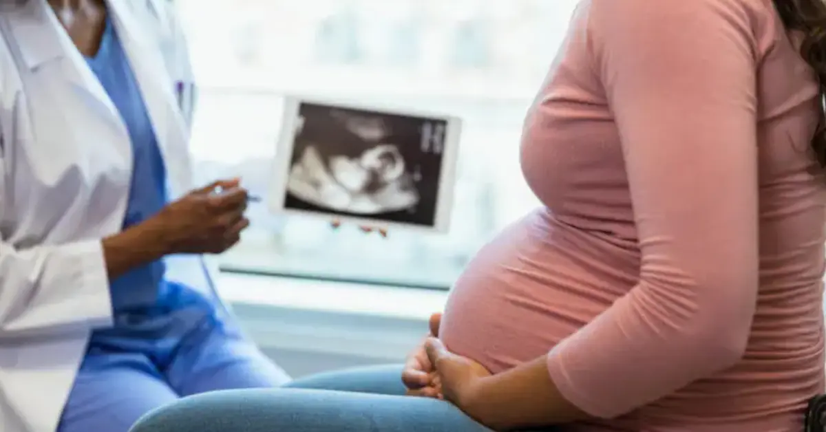 Fertility doctor showing an ultrasound image to a pregnant woman during a prenatal consultation