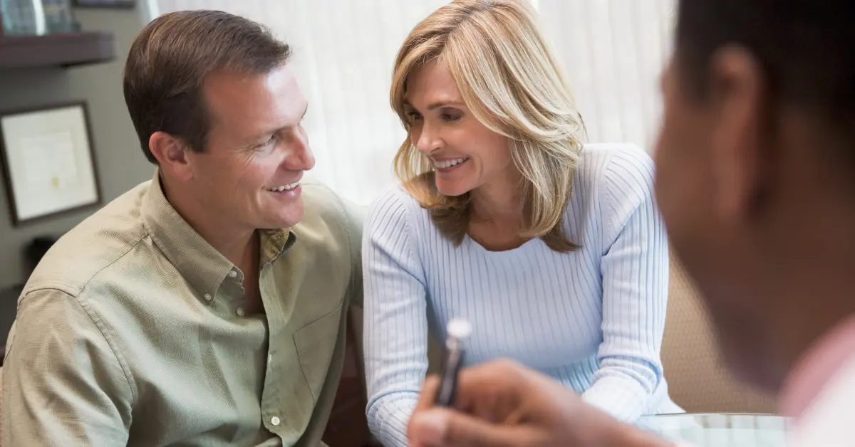 Female hormone balance test discussion with a couple smiling while shaking hands with a fertility specialist.