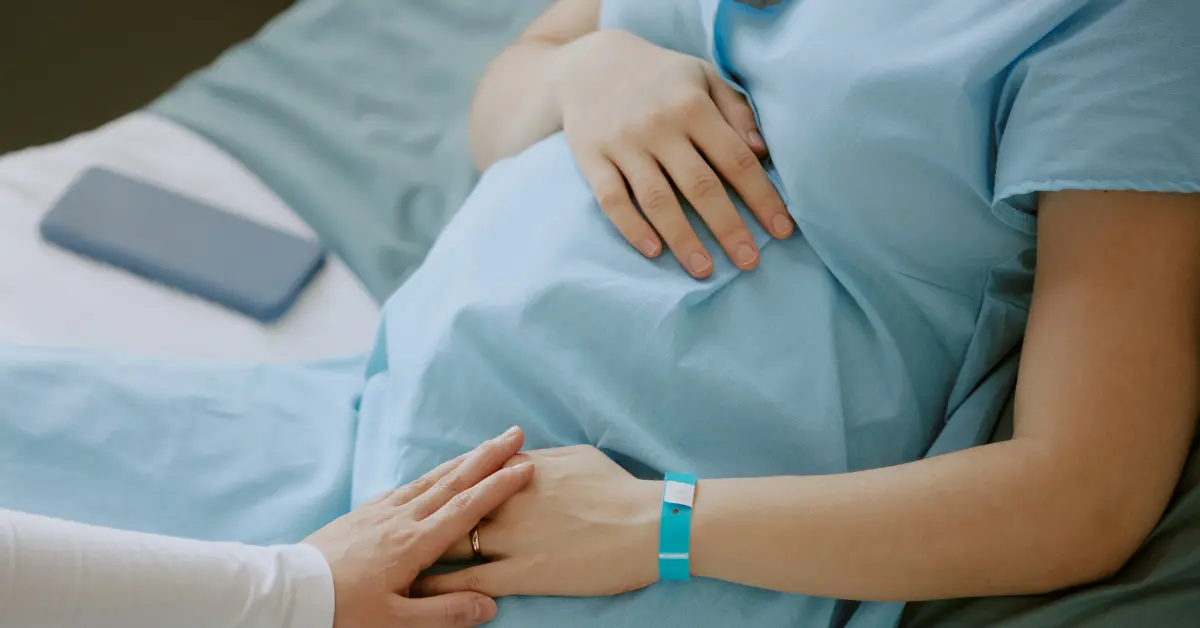 Fertility services support a pregnant woman lying in a hospital bed with hands on her belly
