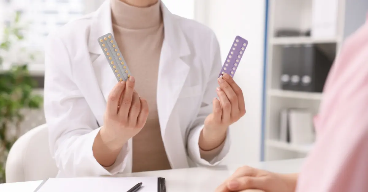 Fertility specialist holding two packs of birth control pills during a patient consultation