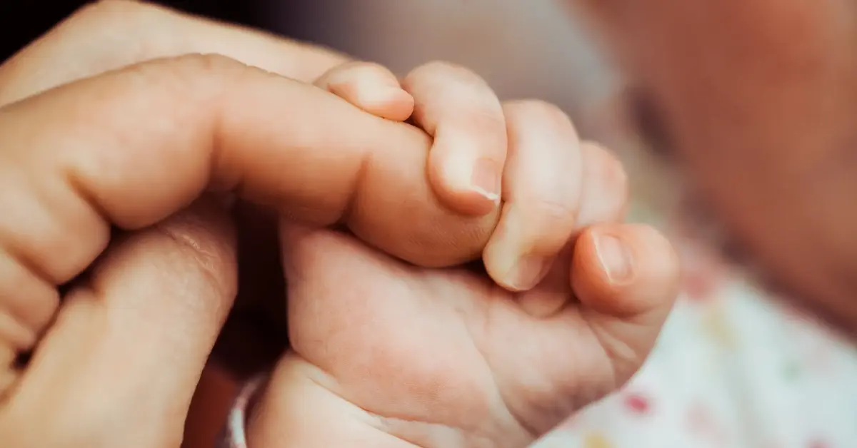 Fertility treatment result shown by a baby tightly grasping a parent's finger