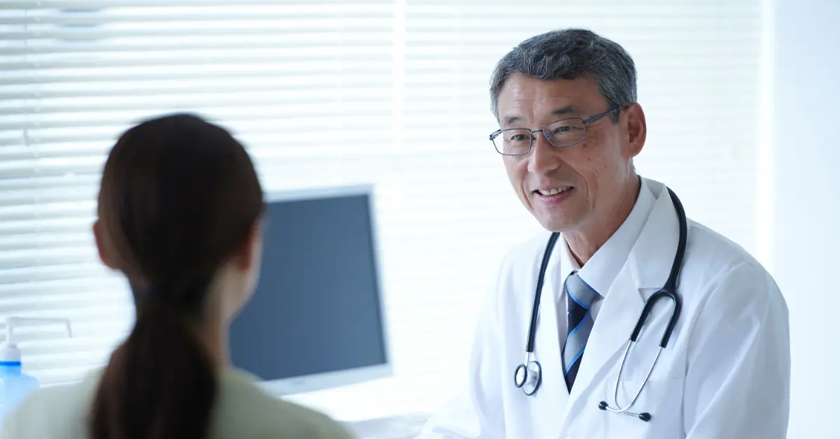 Ovarian function assessment consultation with a doctor smiling while speaking to a female patient in a bright office.