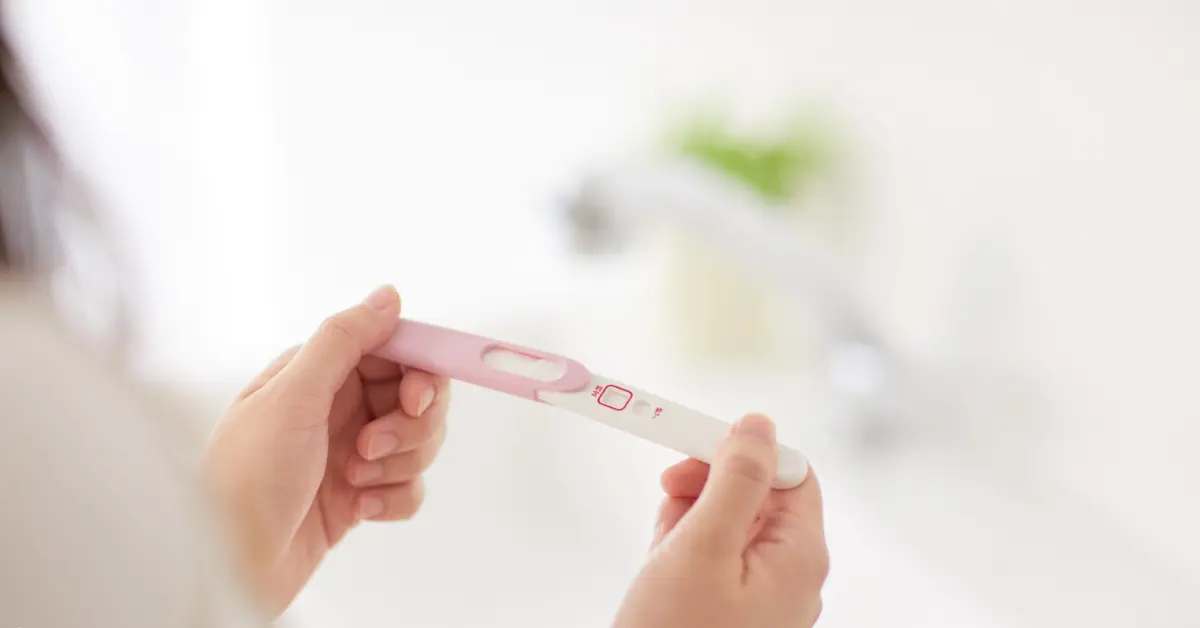 Pregnancy test showing a negative result held in a woman's hands in a bright bathroom