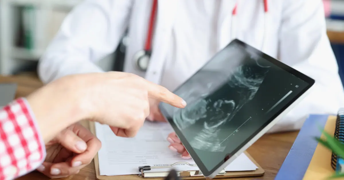 Egg donation process shown as a doctor and patient review an ultrasound image on a digital tablet.