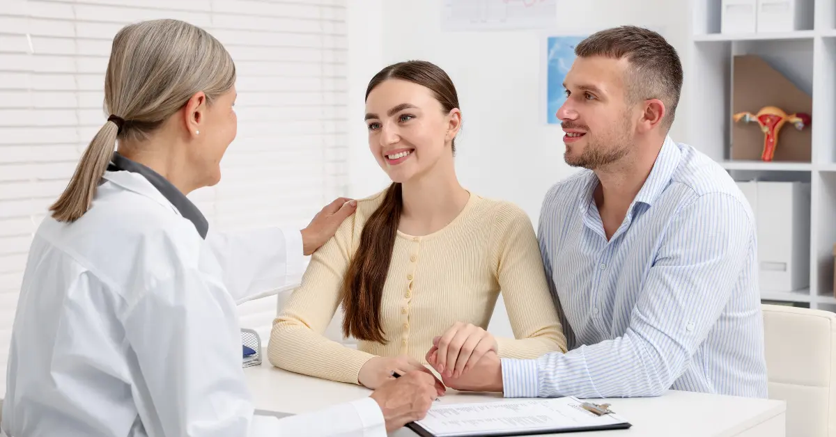 Reproductive health and aging discussion between a smiling couple and doctor during a fertility consultation.