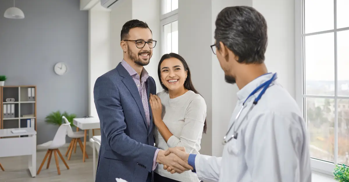 Reproductive hormone testing for men and women discussed as a smiling couple shakes hands with a fertility doctor.