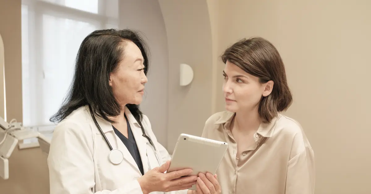 Reproductive specialists consulting with a patient while reviewing results on a tablet in a clinic.